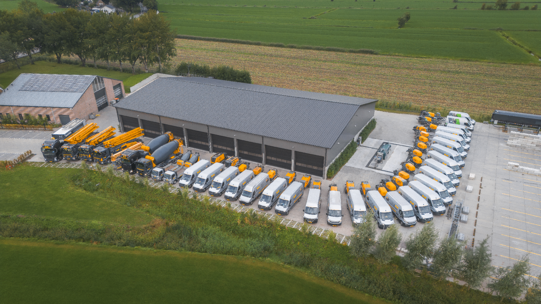 Luchtfoto van het wagenpark van RvR Betonpomp Verhuur met tientallen betonpompen en bussen